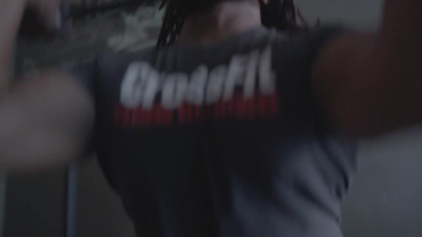 A man is lifting weights repeatedly in a gym during the day