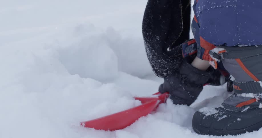 A young boy shovels snow