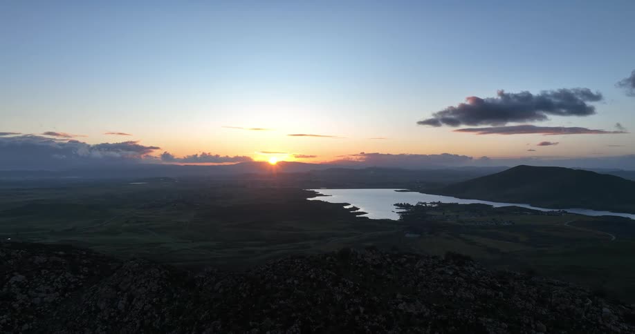 The sun rises over a vast rugged landscape dotted with lakes