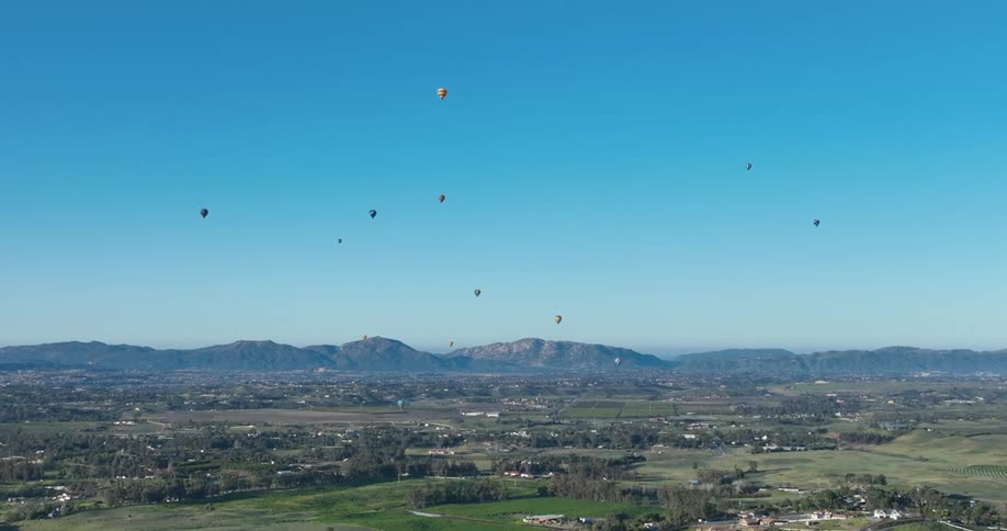 Many hot air balloons float over the land