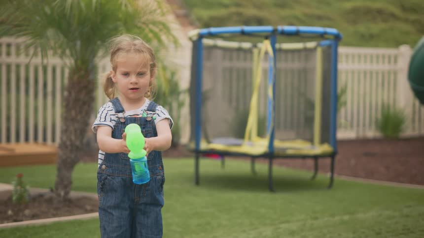Little girl in a garden playing with a bubble gun