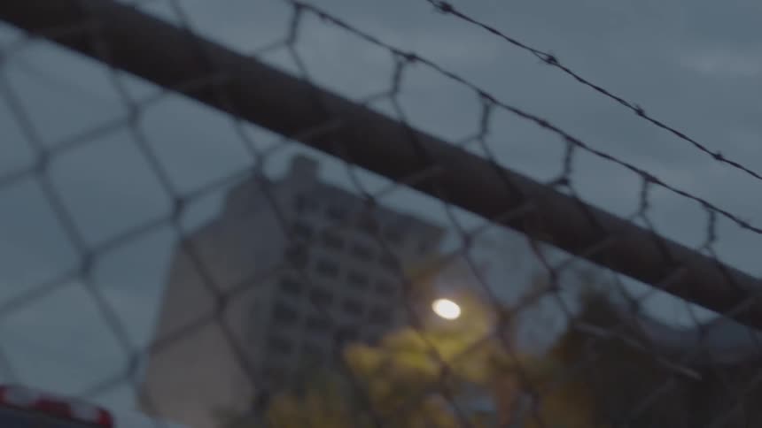 Past a fence are some buildings at dawn
