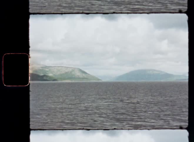 A large lake with a mountain range in the background and a sky full of white clouds