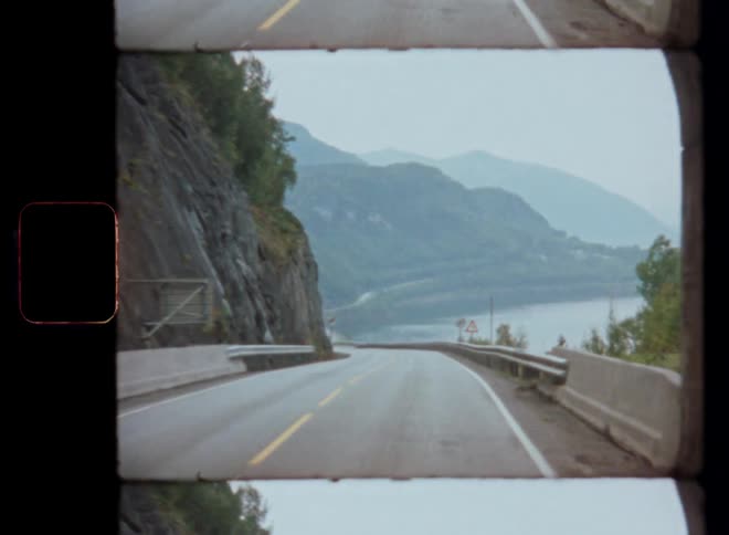 Moving view along a road with a landscape of lake and mountains