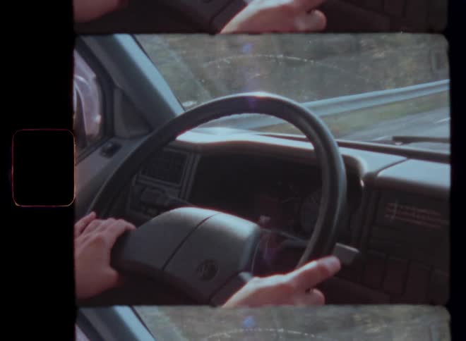 Closeup of a persons hands on a steering wheel with the person wearing a striped sweater
