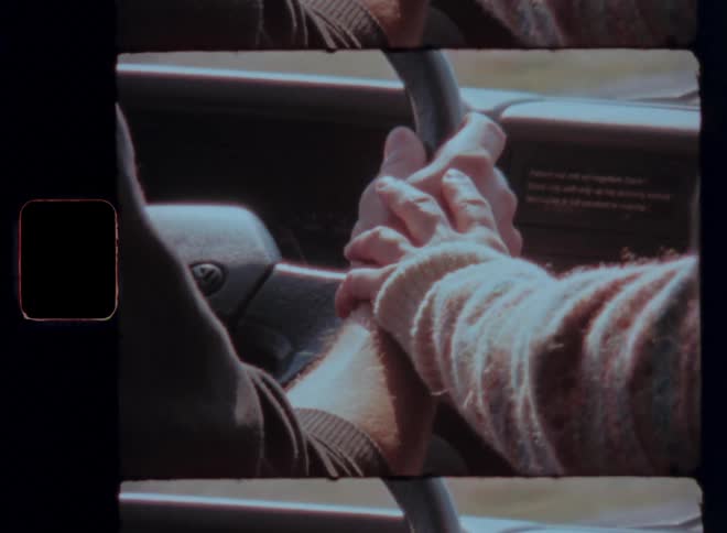 Hand being placed romantically on the arms of a man who is driving