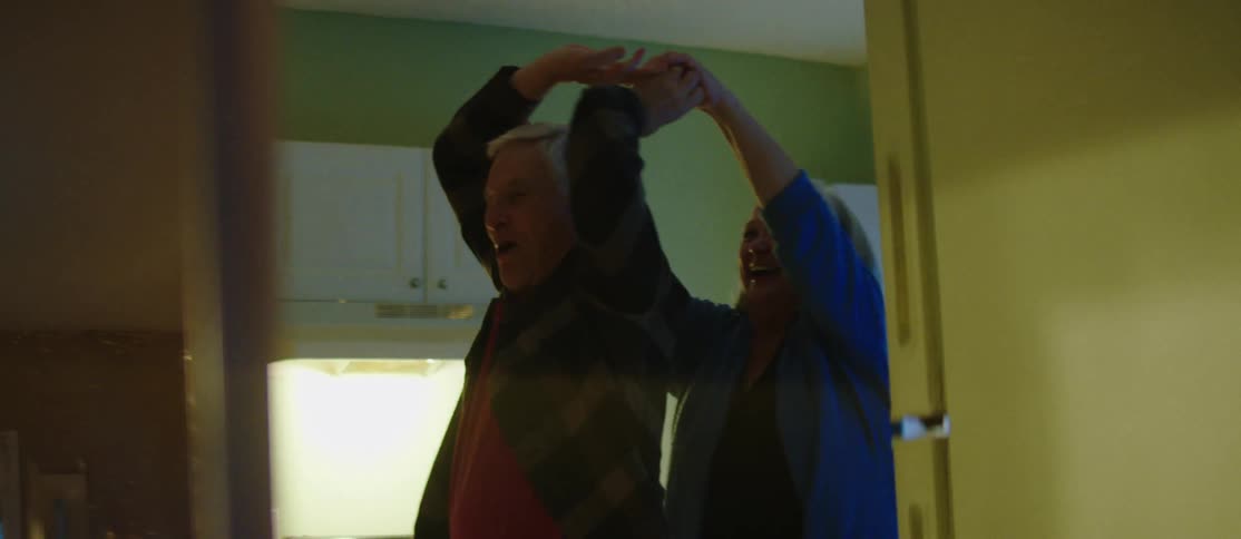 A clip of an elderly couple dancing in the kitchen