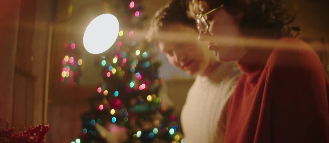 A young couple sits together playing on a musical keyboard during christmas