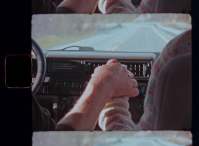 A couple hold hands in a car