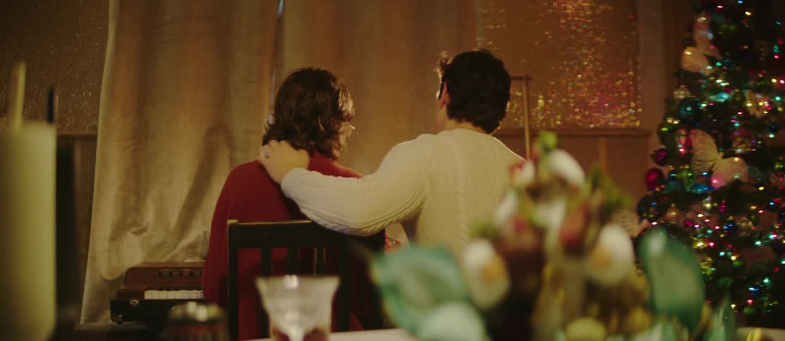View of a couple sitting together in a christmas decorated room in front of a piano
