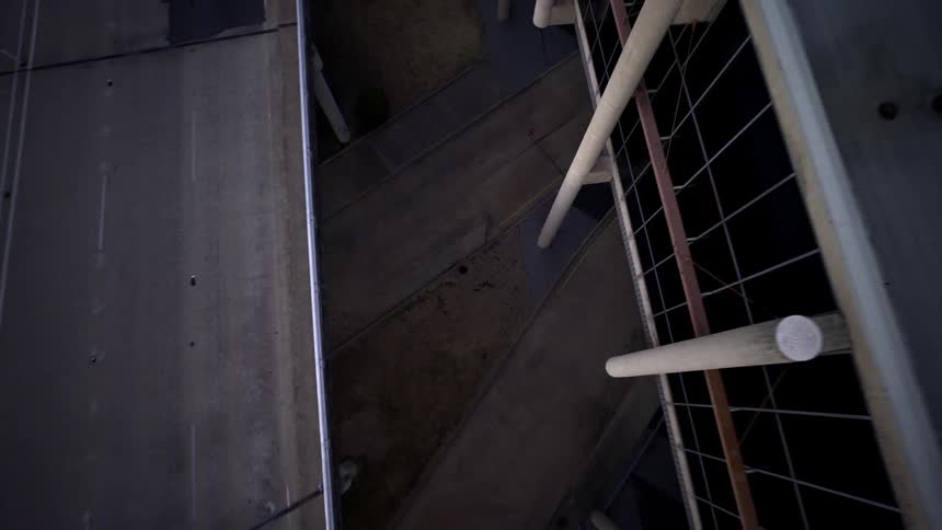 Motorcycle passes under an overpass near a building while a car passes on the overpass