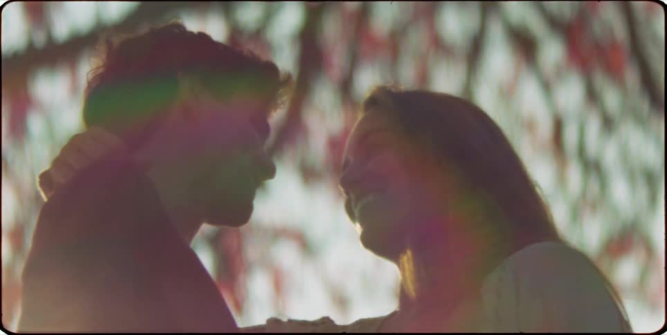 A man and a woman look at each other silhouetted against a bright blurred background