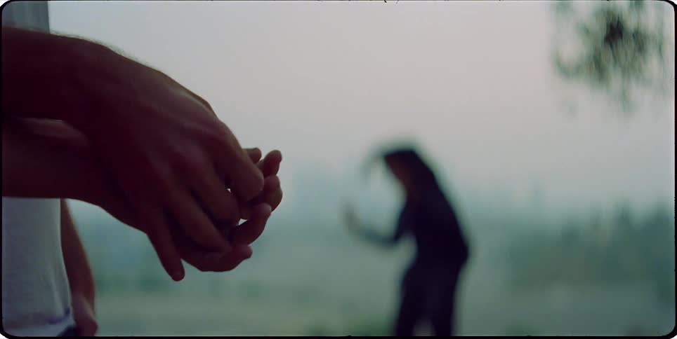 Two people holding hands in the foreground with a blurry figure dancing in the background