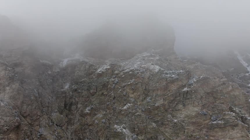 A rugged mountain landscape shrouded in a thick layer of fog creating an atmosphere of mystery and isolation