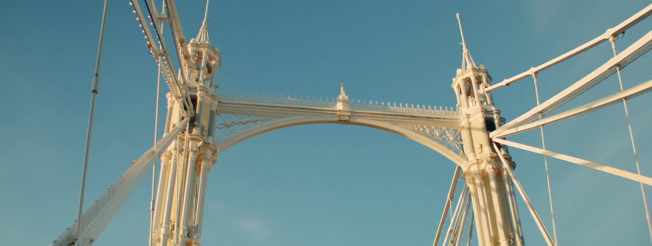 Upward view of a white metal bridge against a blue sky