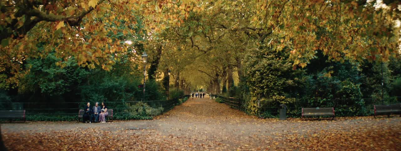 Three people sit on a bench in the park