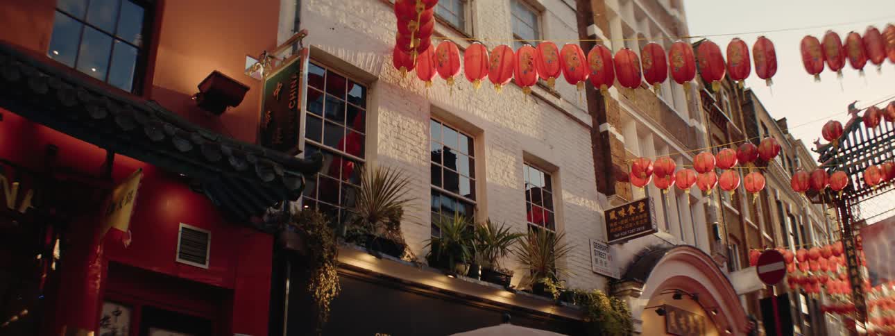 A street scene in chinatown london decorated with numerous red lanterns hanging between buildings