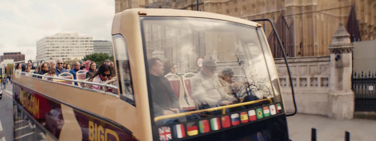 Red tourist bus passing through a public square in a metropolis