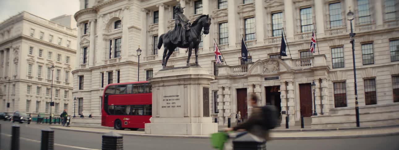 Statue of a man riding a horse next to highways with vehicle traffic and classical buildings in the background