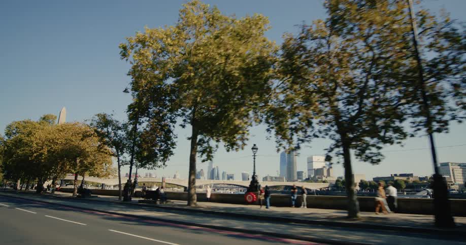 Pedestrians walking on the sidewalk and in the background a bridge and buildings of a metropolis