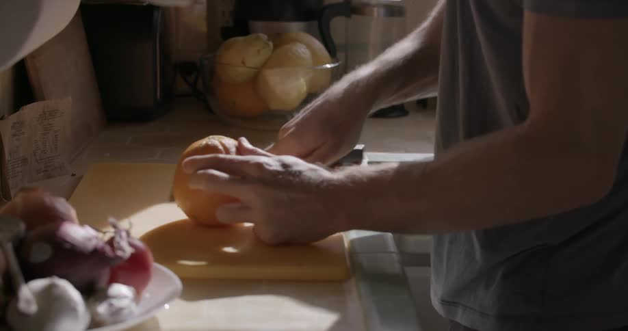 Someone is slicing a grapefruit in half