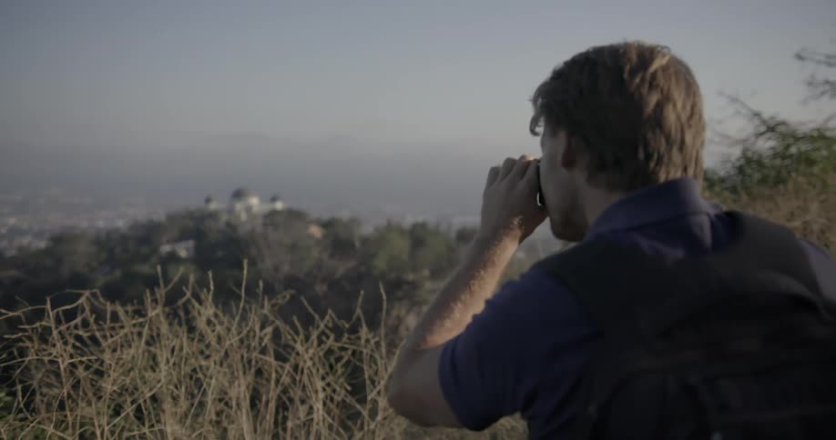 A man takes a photograph while overlooking a valley