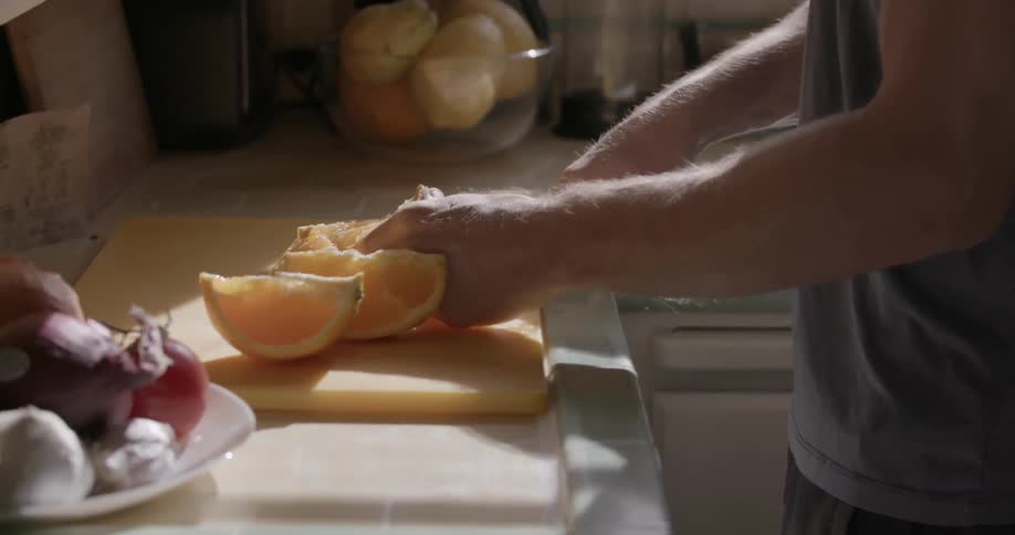 A man is cutting an orange