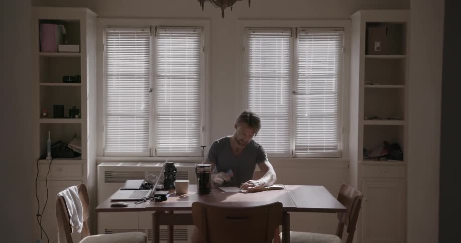 A man is sitting at the kitchen table doing paperwork