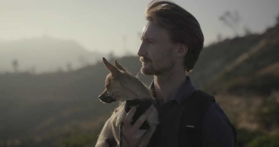 A man holding a dog looking at something off camera