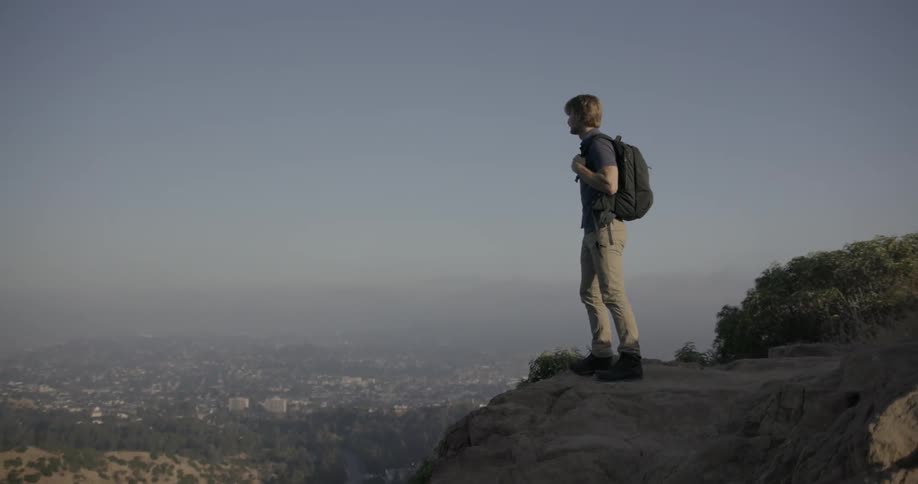 A man walks to the edge of a cliff