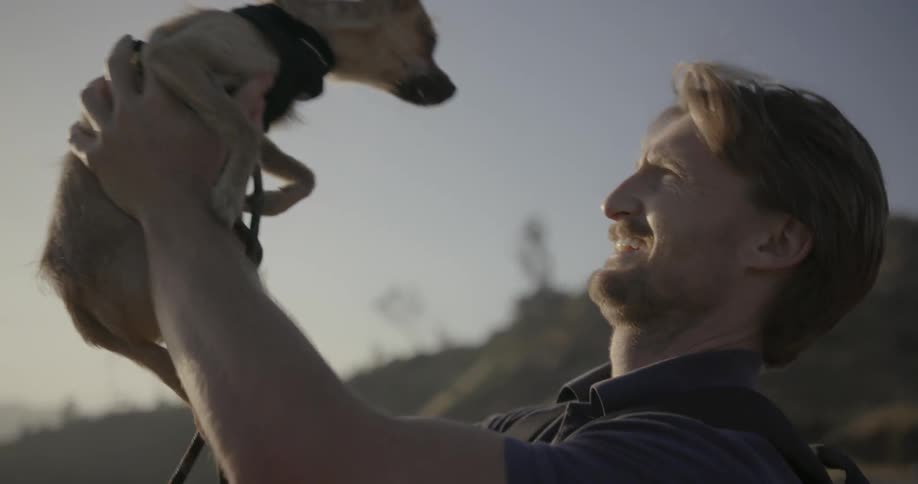 Bearded man holding his small dog on a clear day