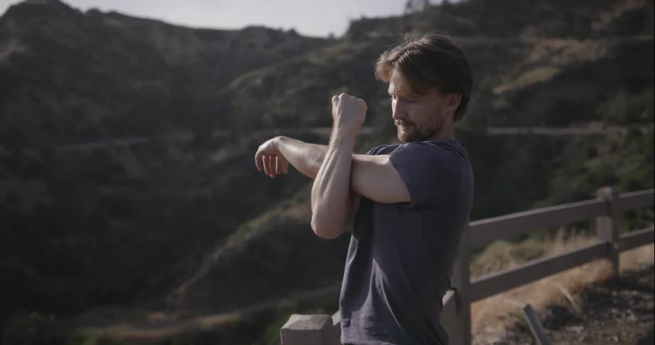 A man is stretching at the top of a mountain