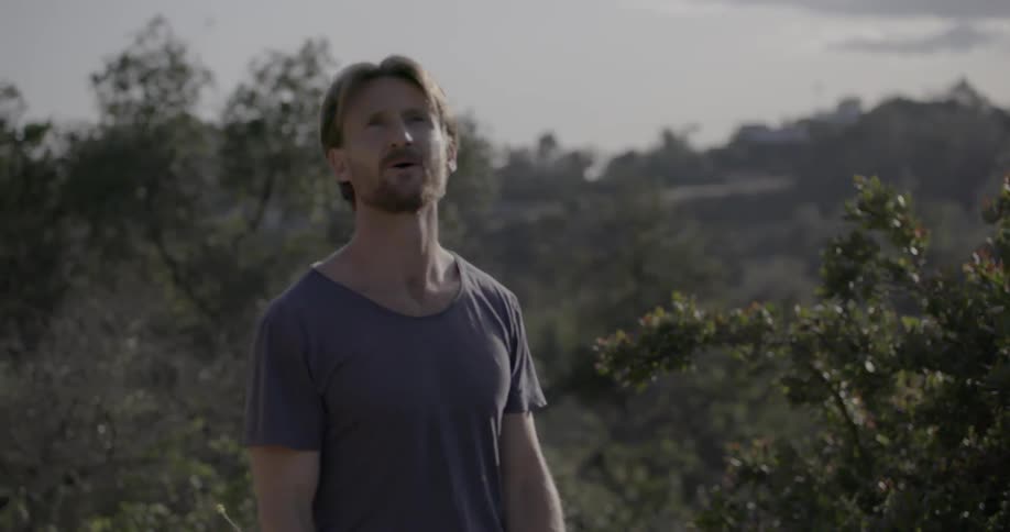 A man stands and looks around a scenic area then jogs off