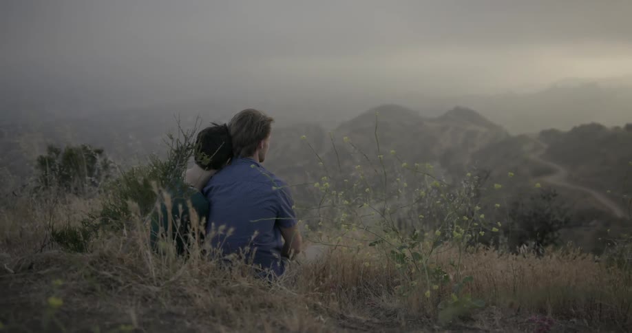 A couple sits atop a hill