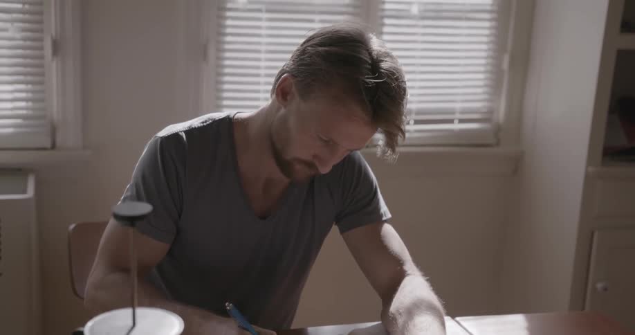 A man is sitting at table writing