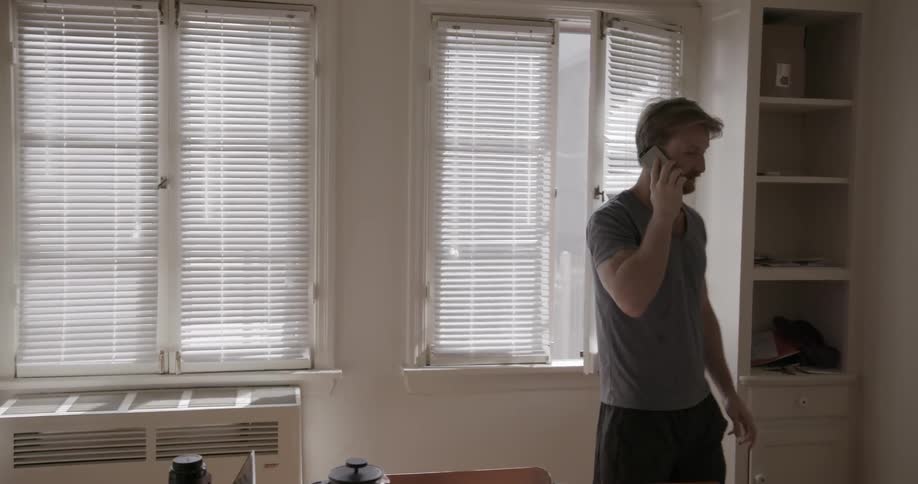 A man paces indoors while talking on the phone