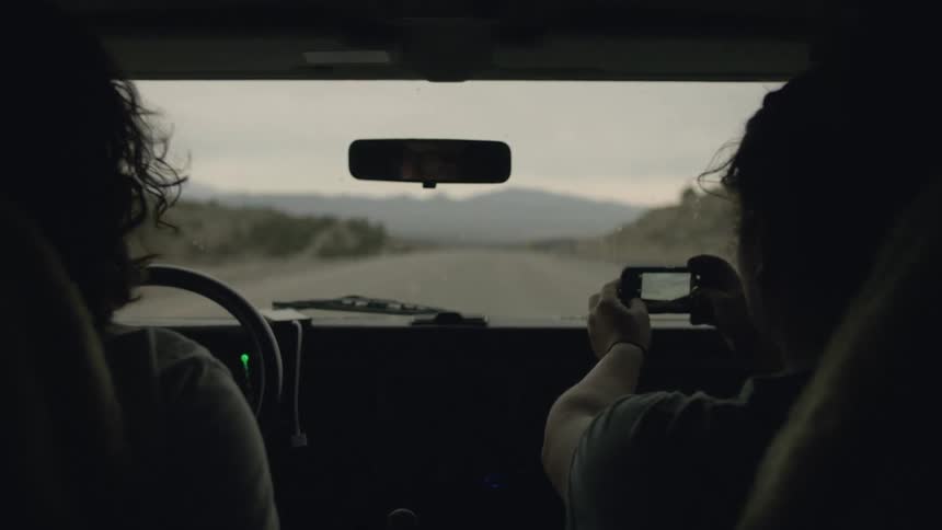 A vehicle travels on a road in the wilderness