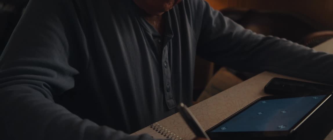 Elderly man sitting writing with a pen