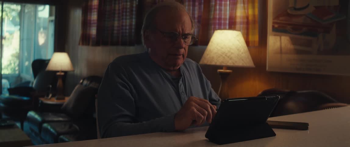 Elderly man sitting and talking in front of a tablet