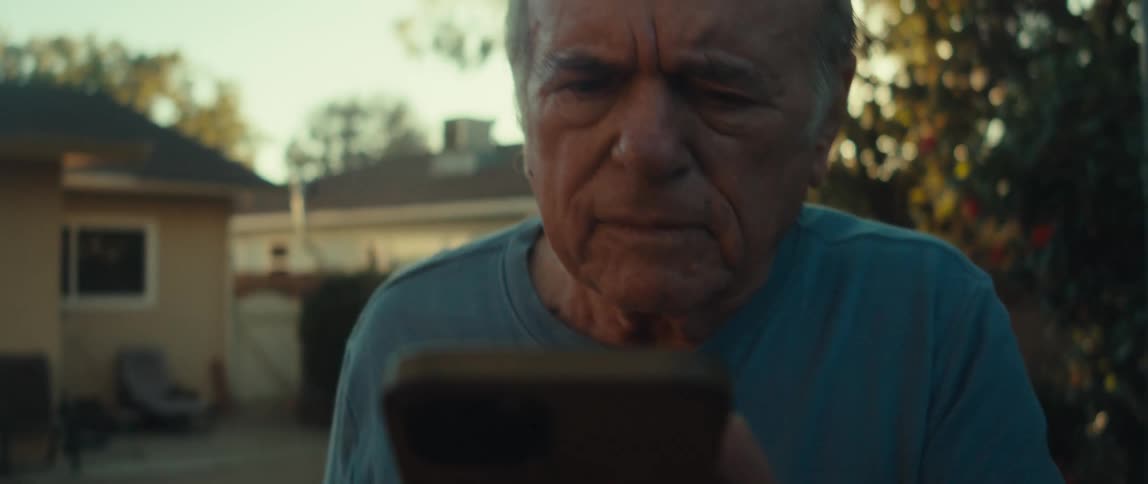 Elderly man walking in a backyard using a cell phone