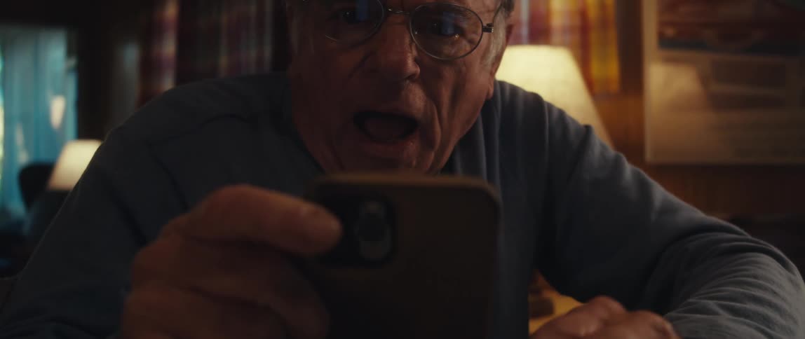 Elderly man interacting with a tablet and then picking up his smartphone and getting happy