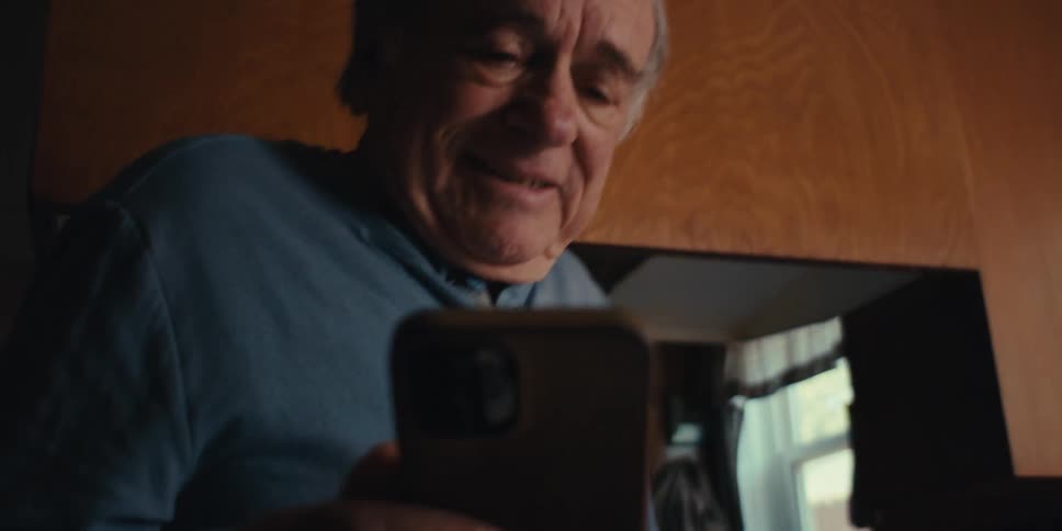 Happy elderly man walking holding a smartphone