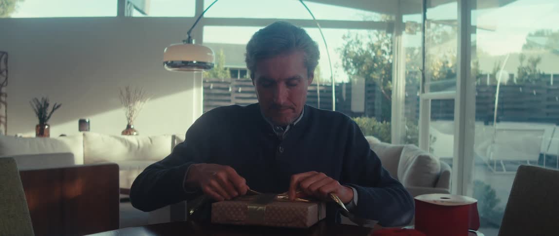 Grayhaired man wrapping a gift