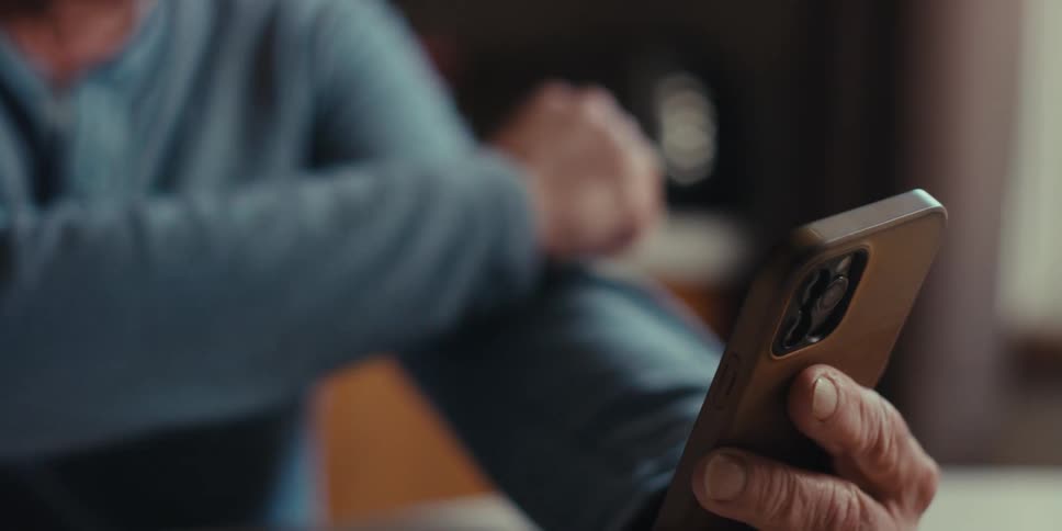 Elderly man laughing while using smartphone