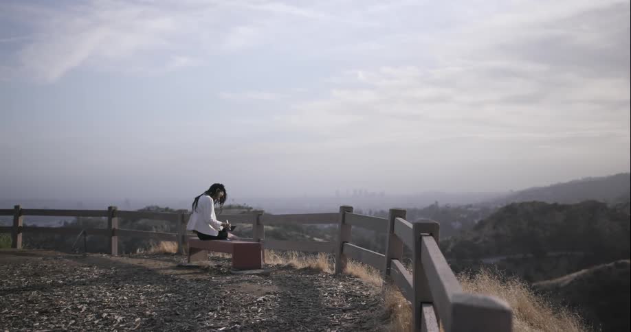 A woman is sitting on a bench reading