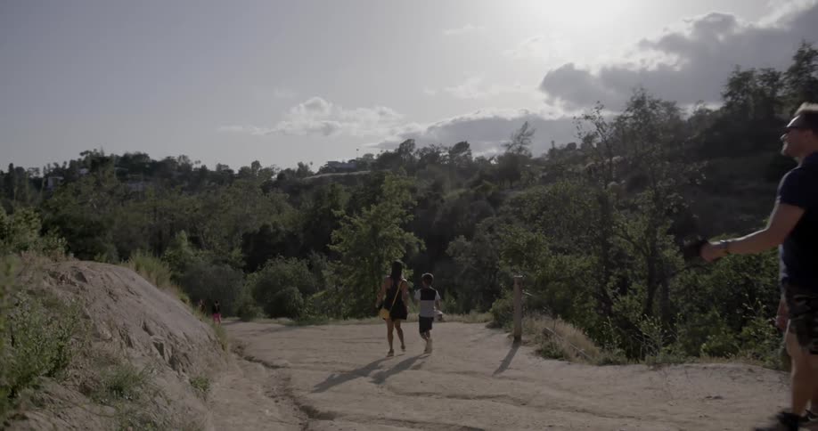 A family walks down a sloping dirt path in nature