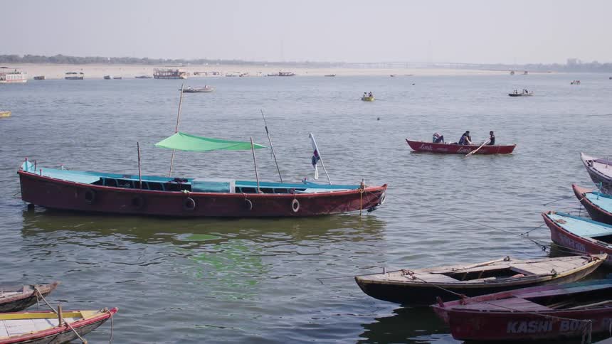 A river with several boats are docked while others have people in them