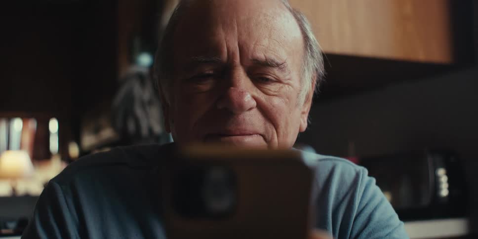A man is smiling while he uses his cell phone