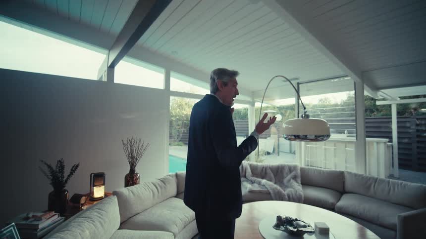 Man in suit walking through living room and talking on cell phone