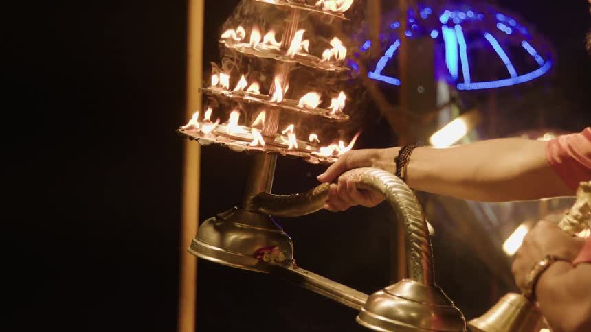 People holding a large candelabra with several layers of small flames burning during a ceremony